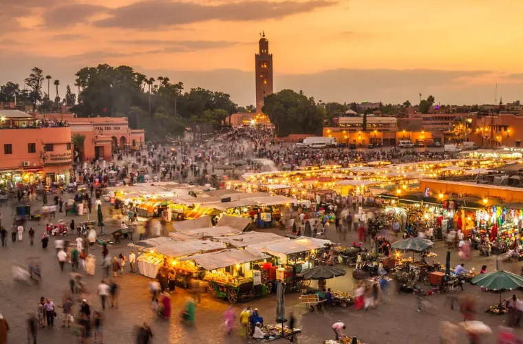 Jemaa el-Fnaa square in Marrakech at sunset with bustling market stalls and Koutoubia Mosque