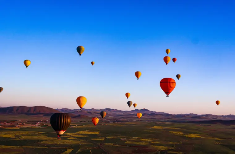 Hot air balloons floating over the Atlas Mountains at sunrise near Marrakech, Morocco